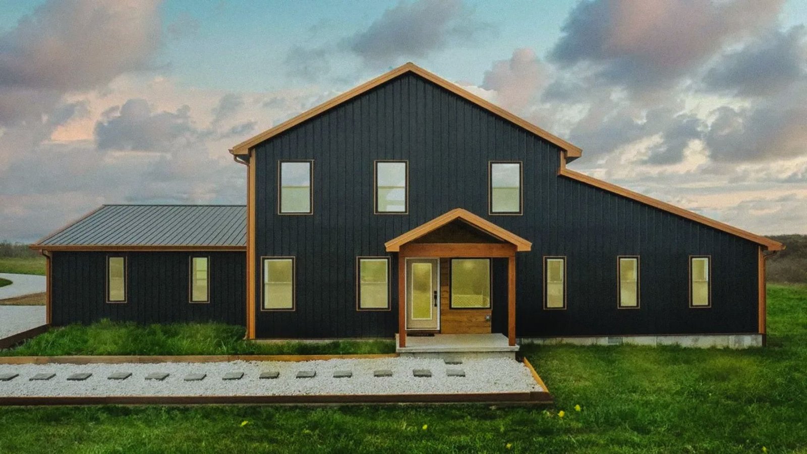A sleek modern black house featuring a spacious front porch, showcasing contemporary architectural design.
