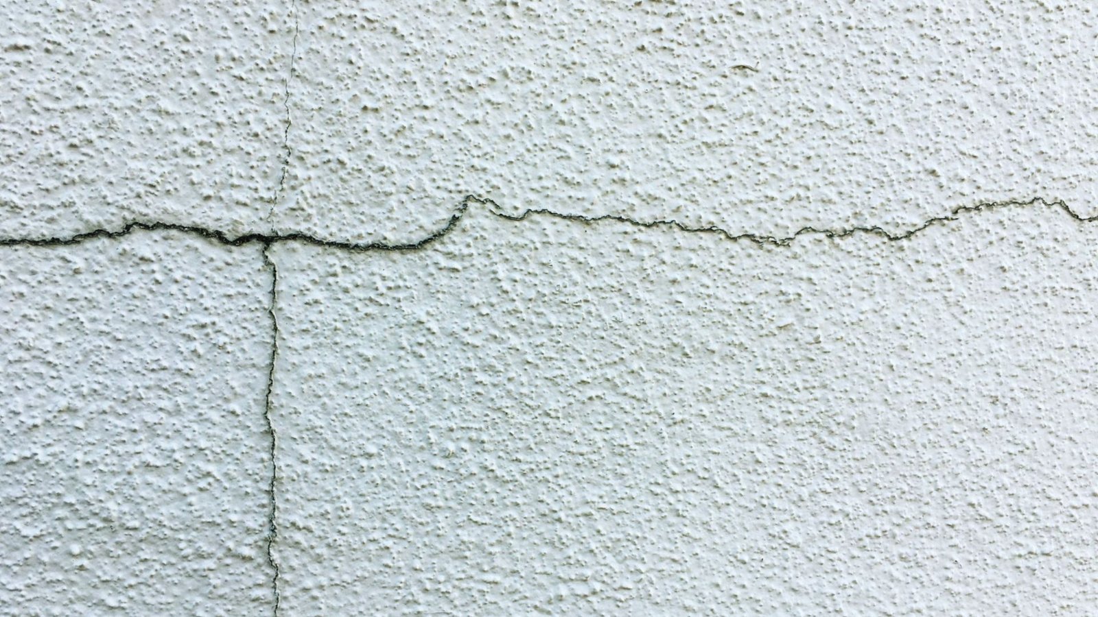 A visible crack in the wall of a white building, highlighting structural damage and wear.