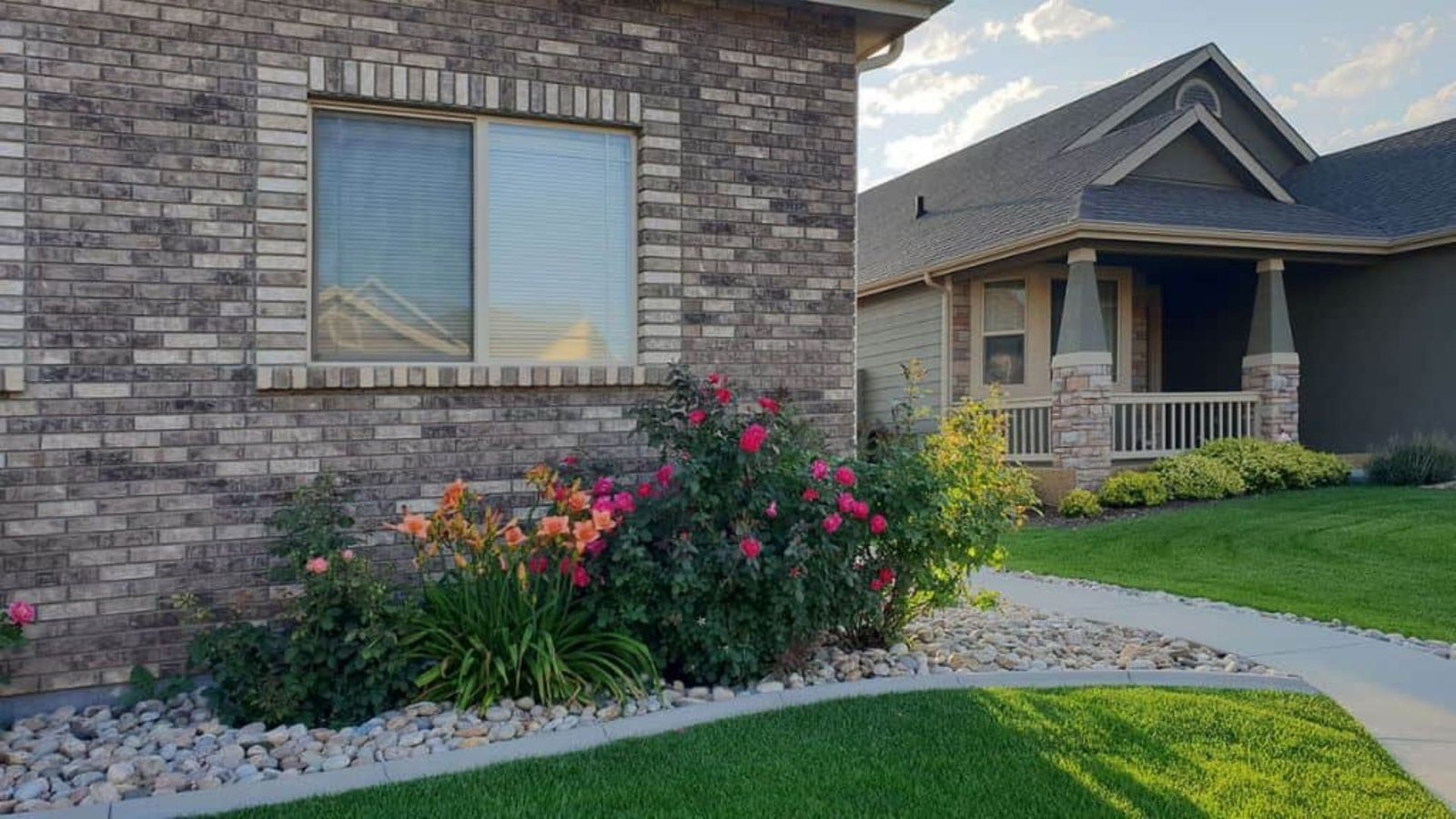 A brick house surrounded by a well-maintained lawn and colorful flowers in bloom.
