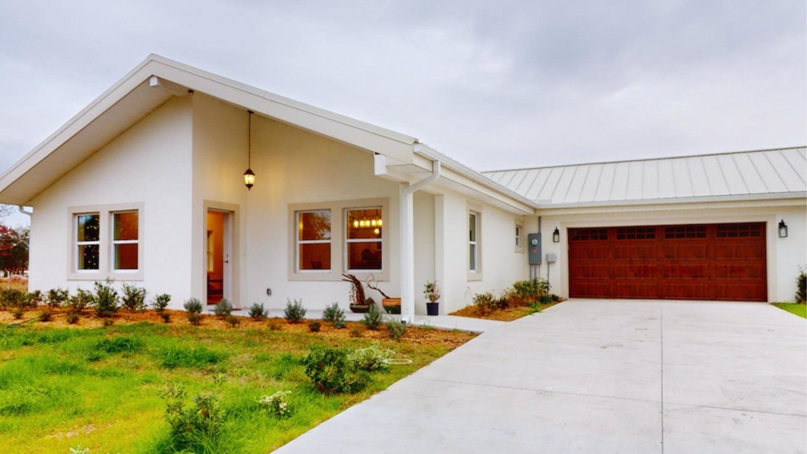 A white house featuring a garage and a paved driveway, set against a clear blue sky.
