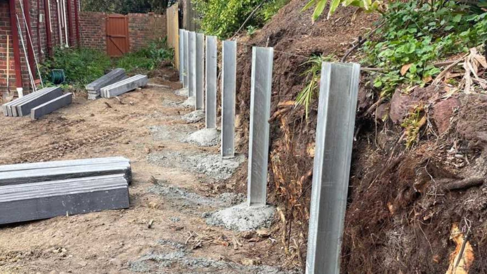 Workers are constructing concrete posts on a hillside, showcasing a developing structure.