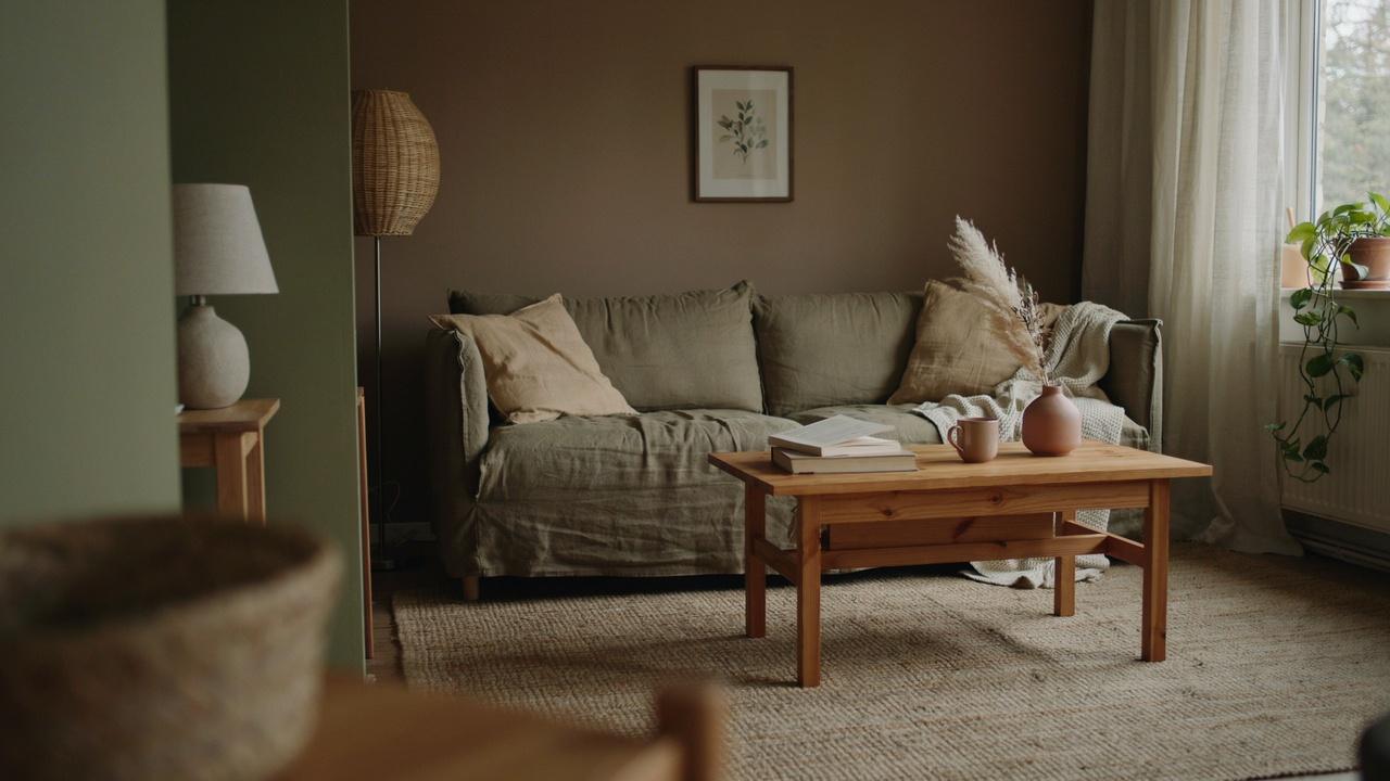 Living room with warm brown walls, olive accents, wood furniture, and earthy decor.