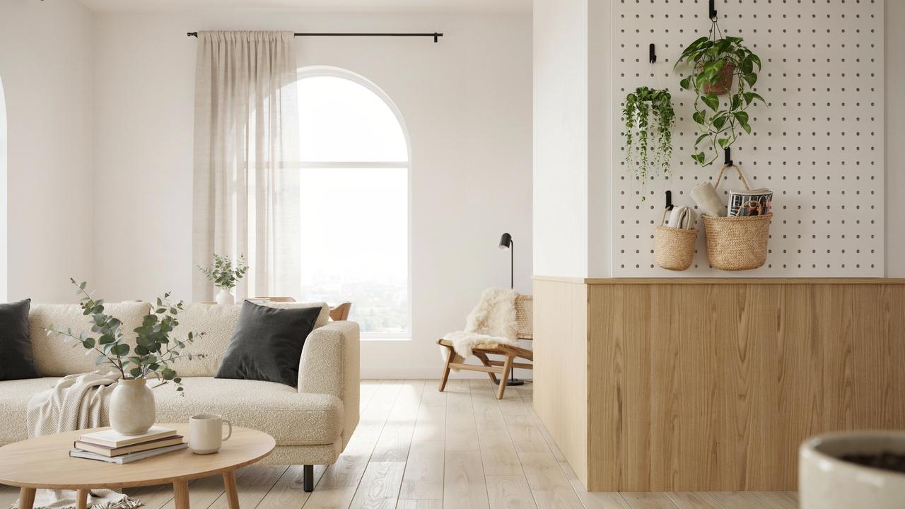 Half wall room divider with white pegboard storage, hanging plants, and organized accessories in a modern living room.