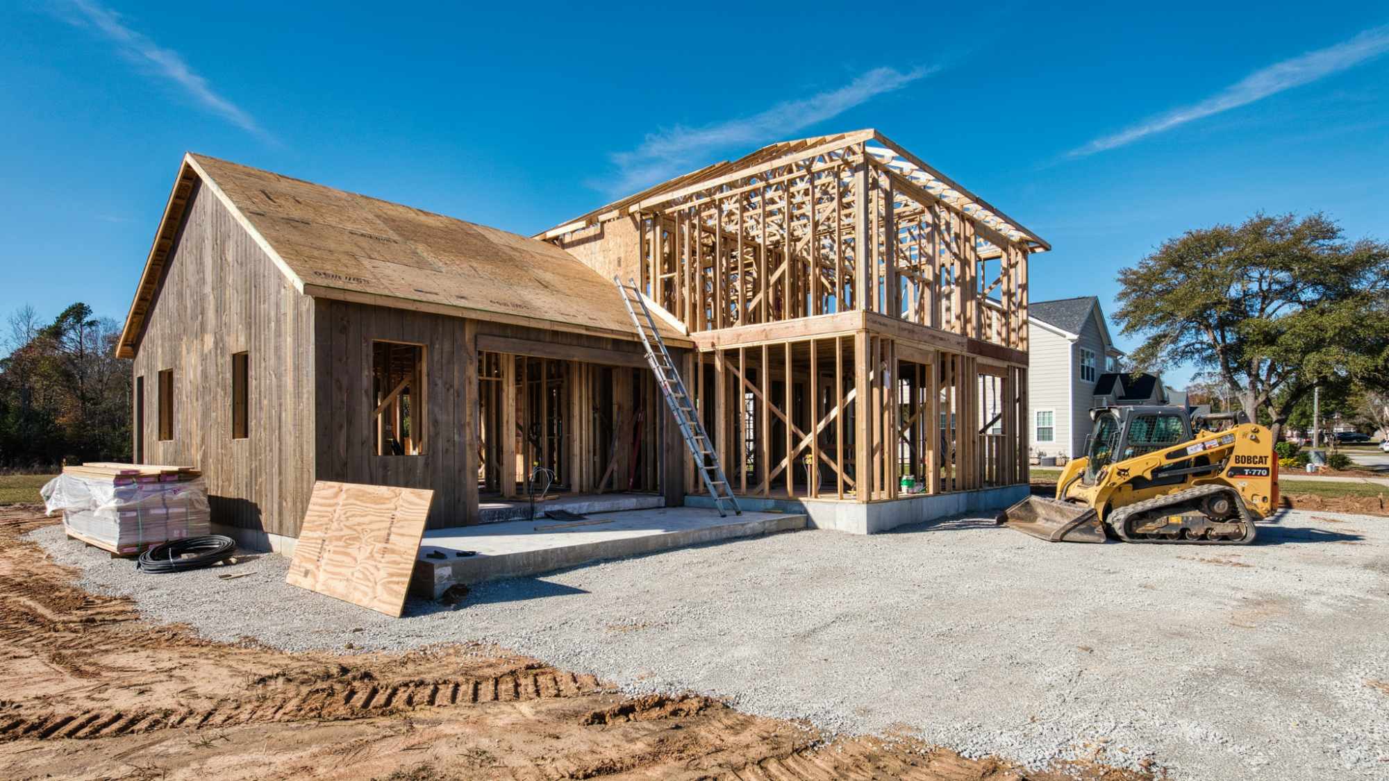 Custom home construction showing foundation, framing, and exterior structure.