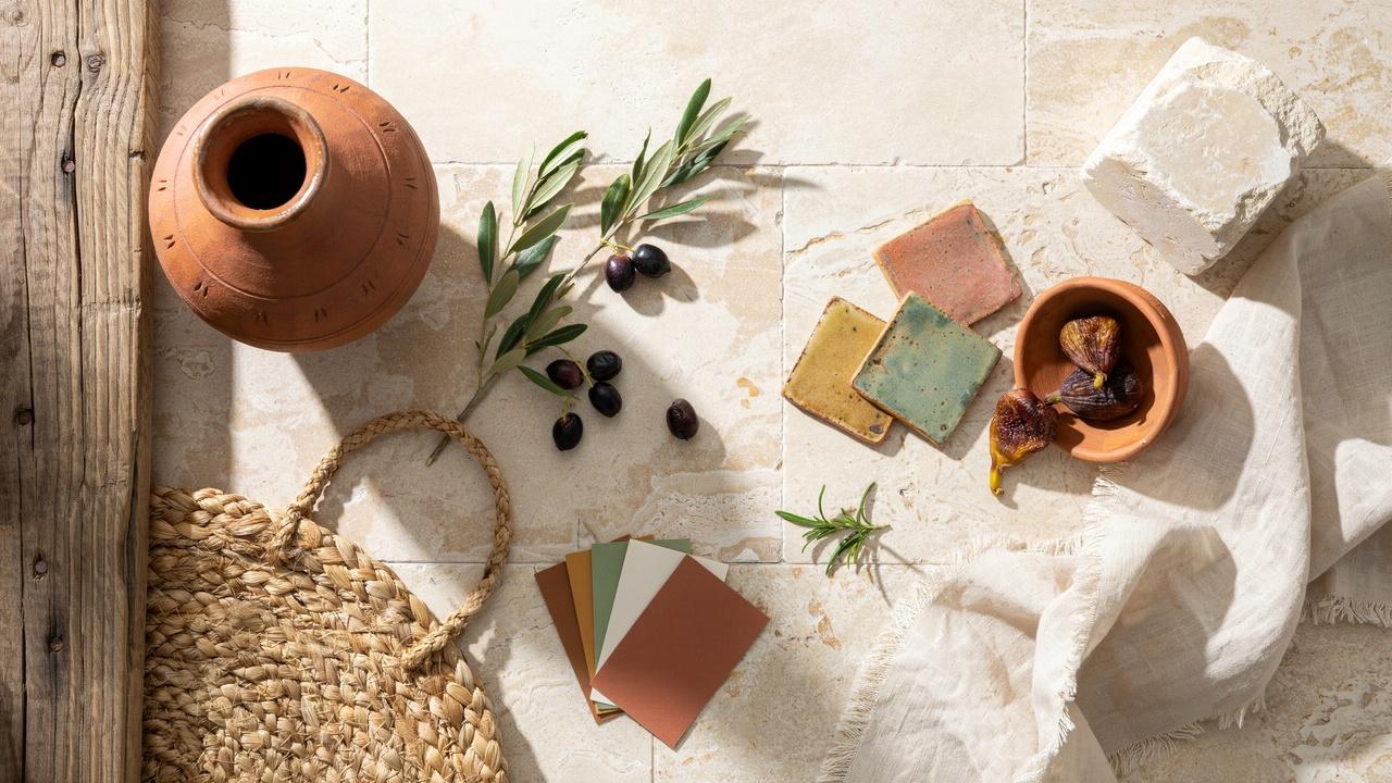 Mediterranean design elements featuring terracotta pottery, olive branches, woven baskets, natural stone, wood, and earthy colors.