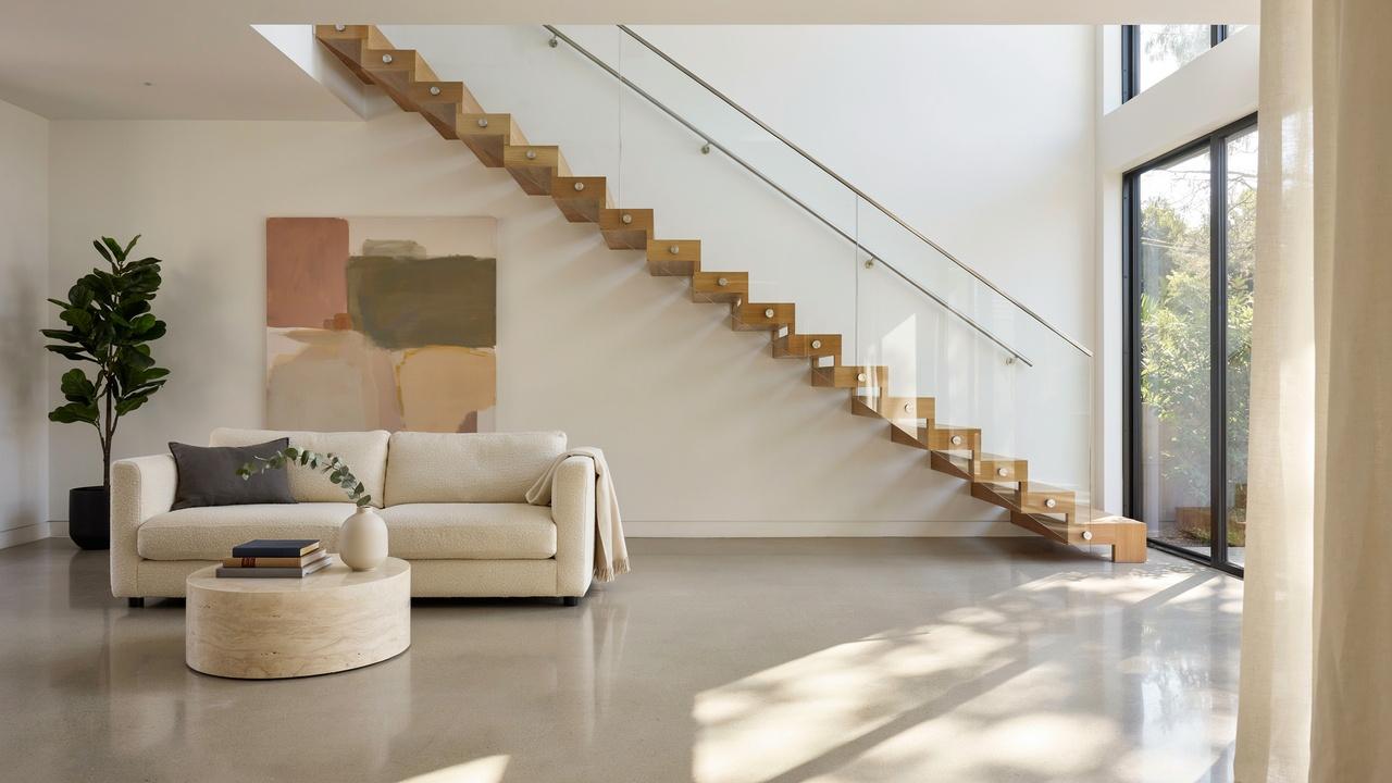 Modern floating staircase with glass railings in a bright contemporary home.